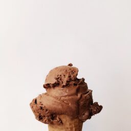 A scoop of chocolate ice cream on a cone.