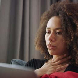 Sick woman feeling her throat.