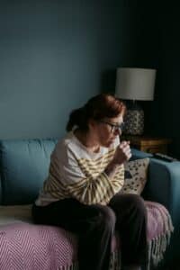 A woman sitting on a couch and coughing.