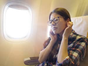 Woman experiencing ear pain while flying.