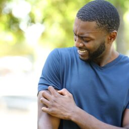 Man scratching arm in park