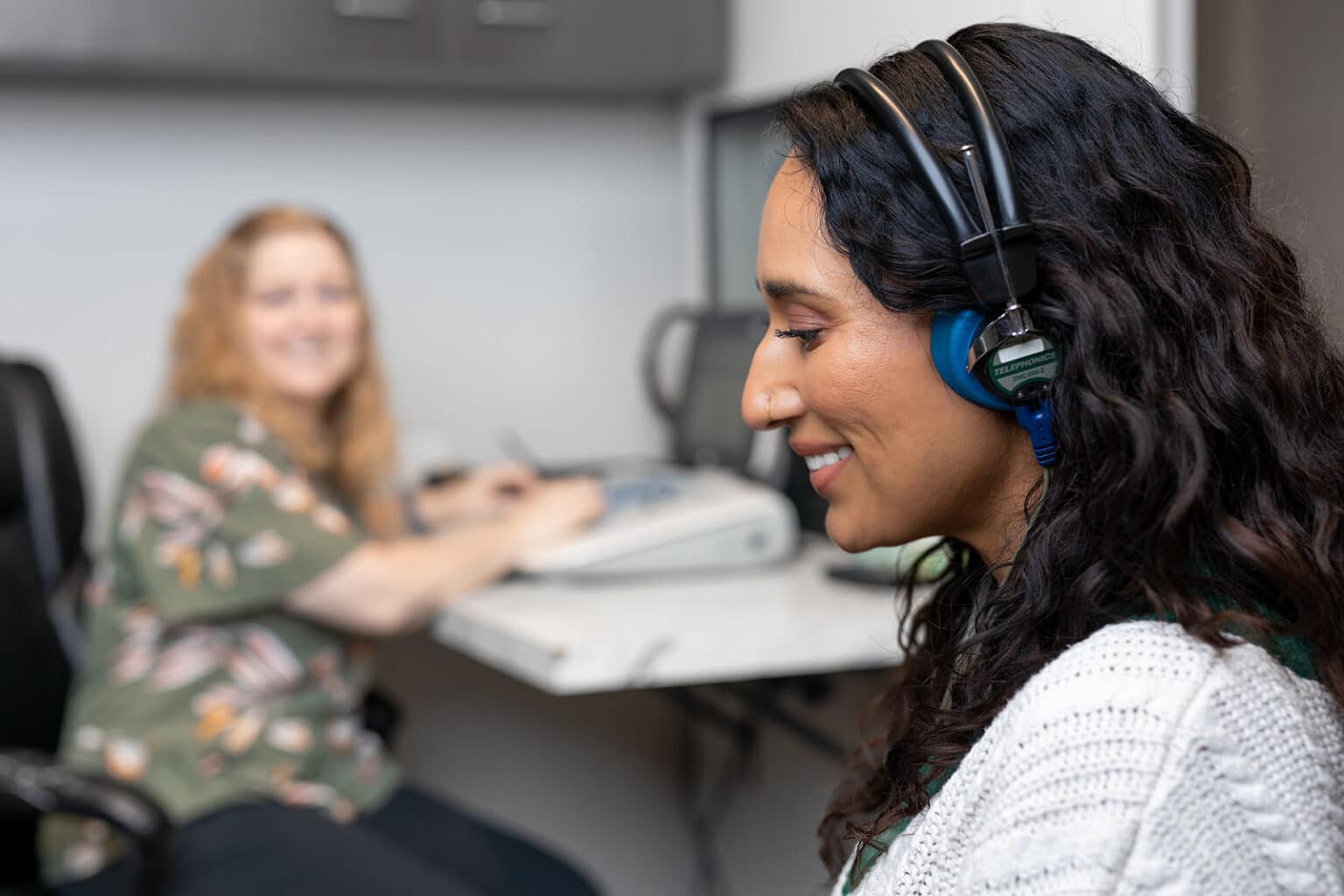 Woman in an audiologists office with headphones on listening intently during a hearing test