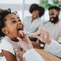 Pediatrician diagnosing throat infection with tongue depressor