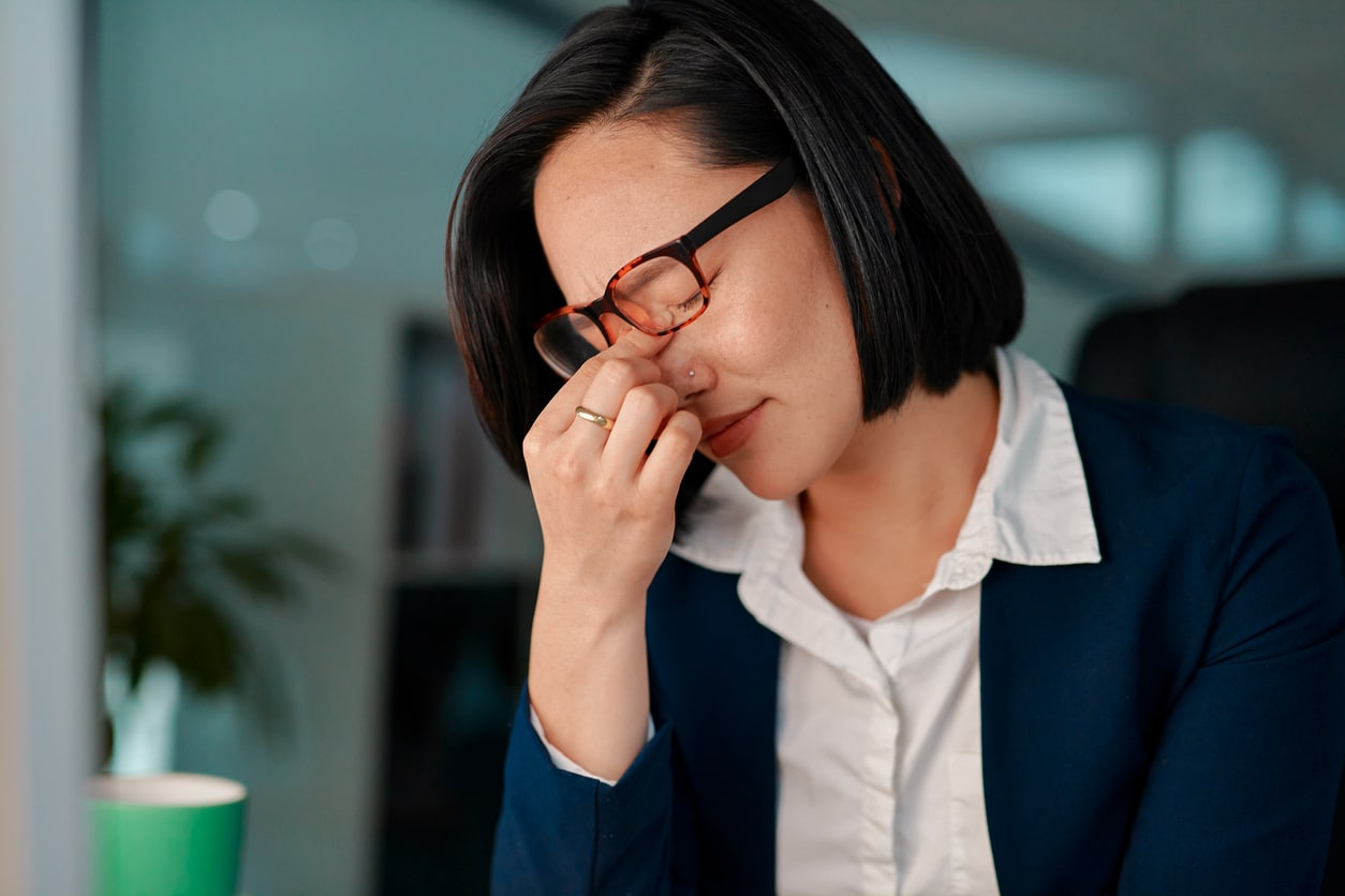 Young woman holding the bridge of her nose under her glasses.