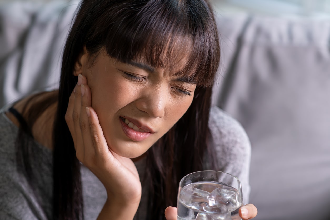 Young woman with a toothache holding her sore jaw.