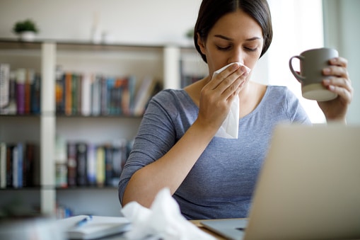 Woman blowing her nose into a tissue.