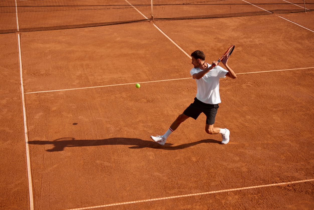 Dynamic image of athletic young man, tennis player in motion on court.