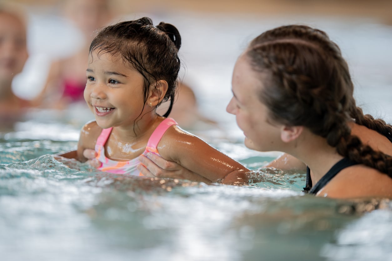 Child Enjoying a Swim Lesson at an Indoor Community Pool 