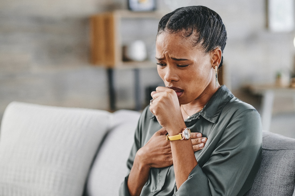 Coughing woman sitting on her couch. 