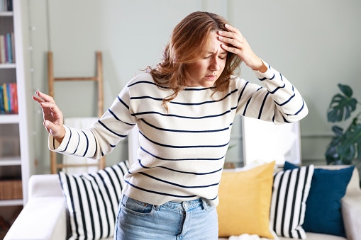 Young woman with vertigo holding her head.